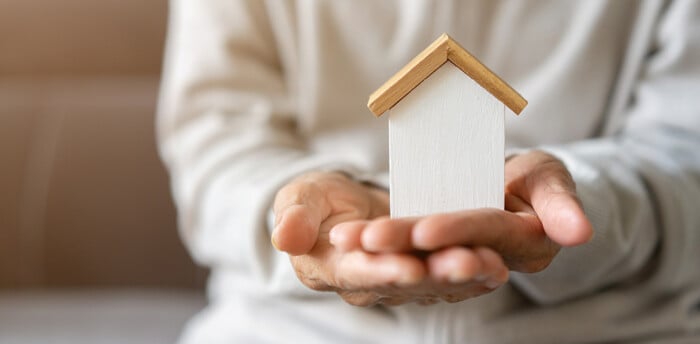 Close Up Senior Woman Hand Hold Wood Home Model For Welfare And