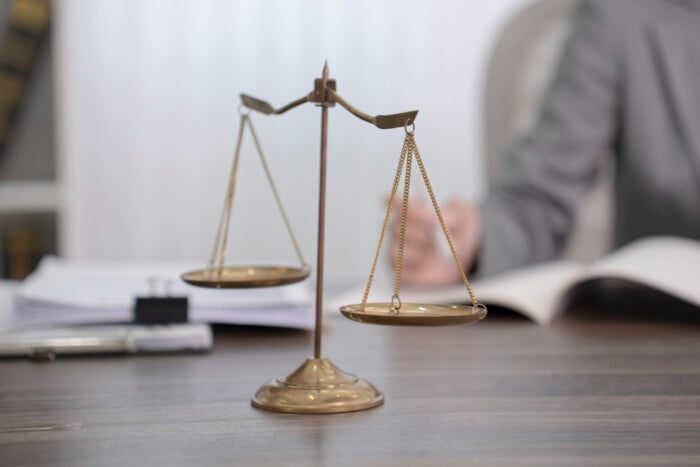 A Pair Of Vintage Golden Scales Of Justice Rests On A Wooden Des
