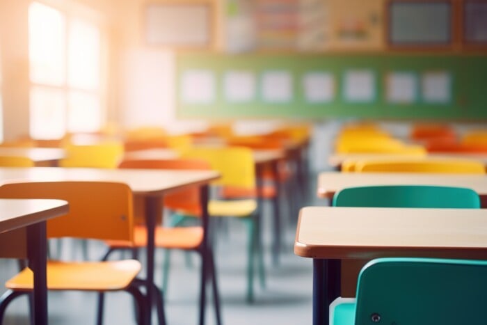 School Classroom In Blur Background Without Young Student. Blurry View Of Elementary Class Room No Kid Or Teacher With Chairs And Tables In Campus. Back To School Concept