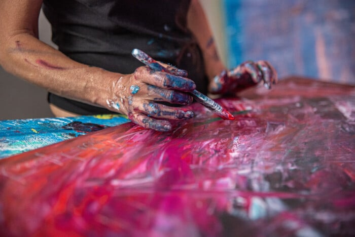 Young Woman Paints An Abstract Picture With Her Hands In Her Int
