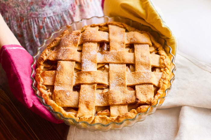 Housewife In Oven Glove Hold The Apple Pie In The Kitchen. Woman