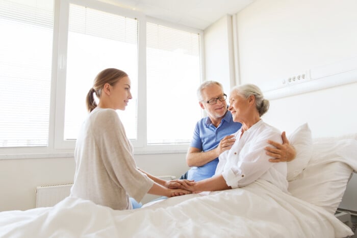 Happy Family Visiting Senior Woman At Hospital