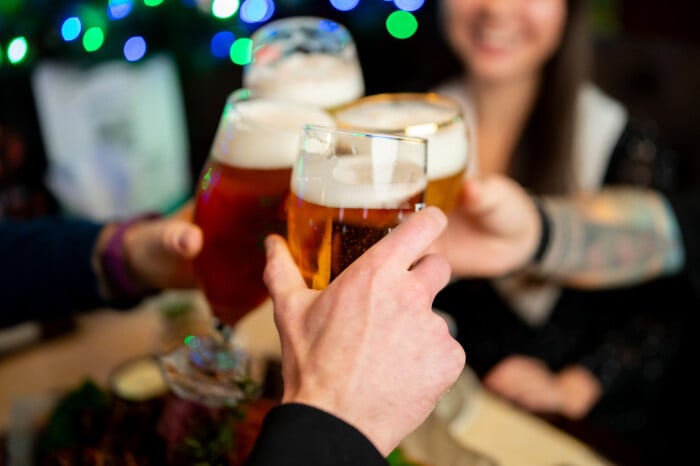 A Group Of Friends Making A Celebratory Beer Toast In A Lively B