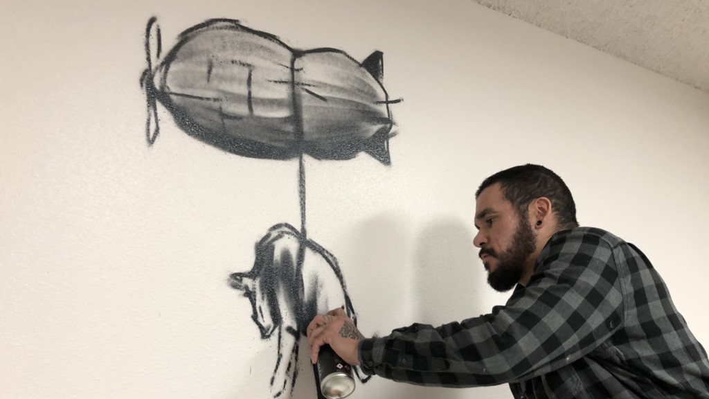 Godfitti draws on a wall.