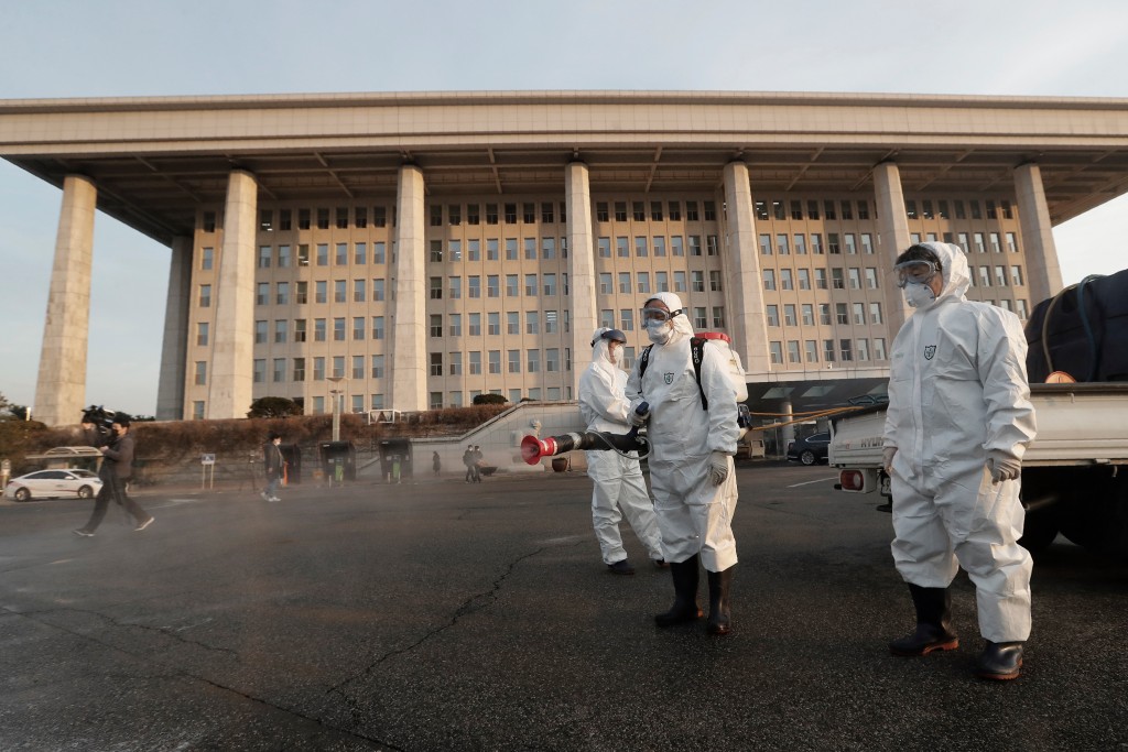 Workers wearing protective suits spray disinfectant as a precaution against the coronavirus at the National Assembly in Seoul.