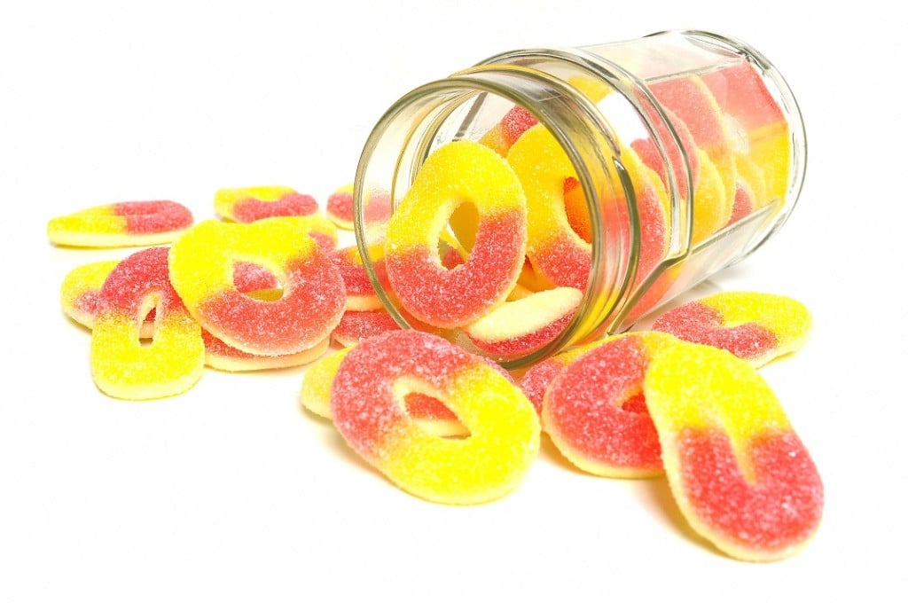 Peach,flavored,candy,rings,and,glass,jar,on,white,background