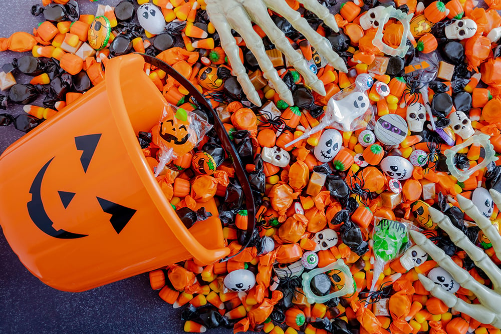 Orange,pumpkin,pail,spilling,halloween,candy,on,black,stone,surface