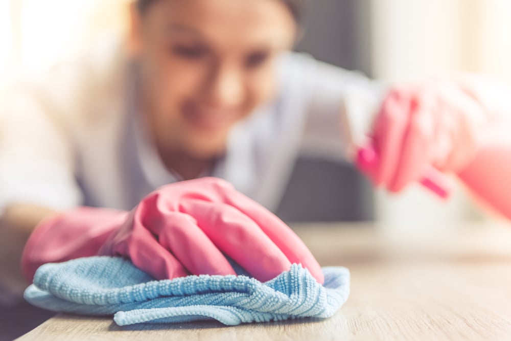 Woman,in,protective,gloves,is,smiling,and,wiping,dust,using