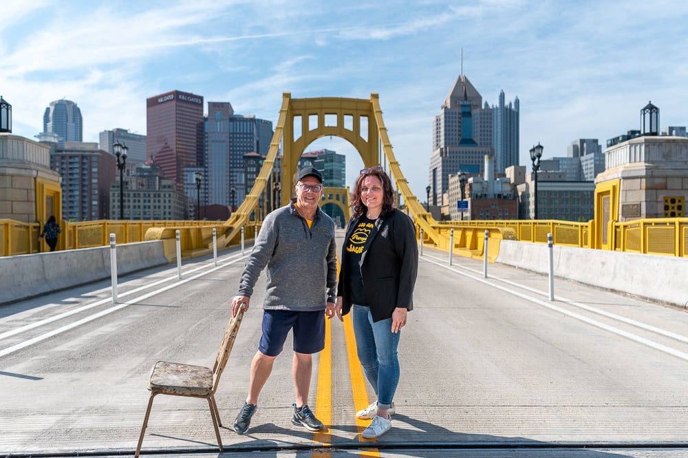 Rachael And John On Bridge With Chair Looking At Camera