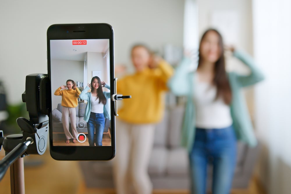 Asian Young Woman With Her Friend Tiktoker Created Her Dancing Video By Smartphone Camera Together. To Share Video To Social Media Application