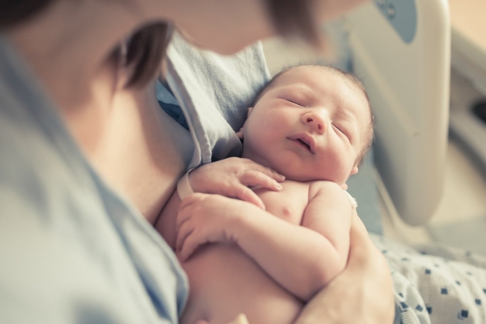 Parenting And New Life Concept. Mother Holding Newborn Baby Boy In Her Arms.