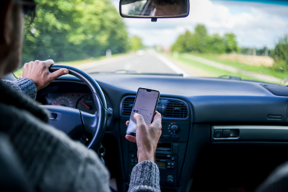 A Man Use Smartphone While Driving In The Car. Road Danger Concept