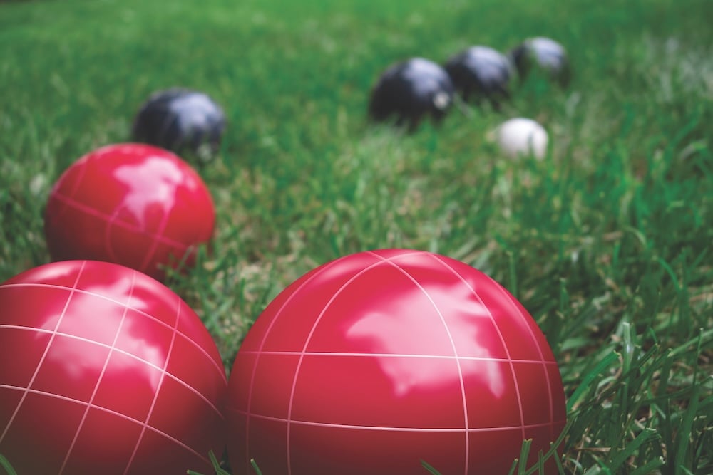 Italian Bocce Ball, Bocci Or Boccie Red And Blue White Balls On Green Lawn Close Up. An Ancient Games Played In The Roman Empire