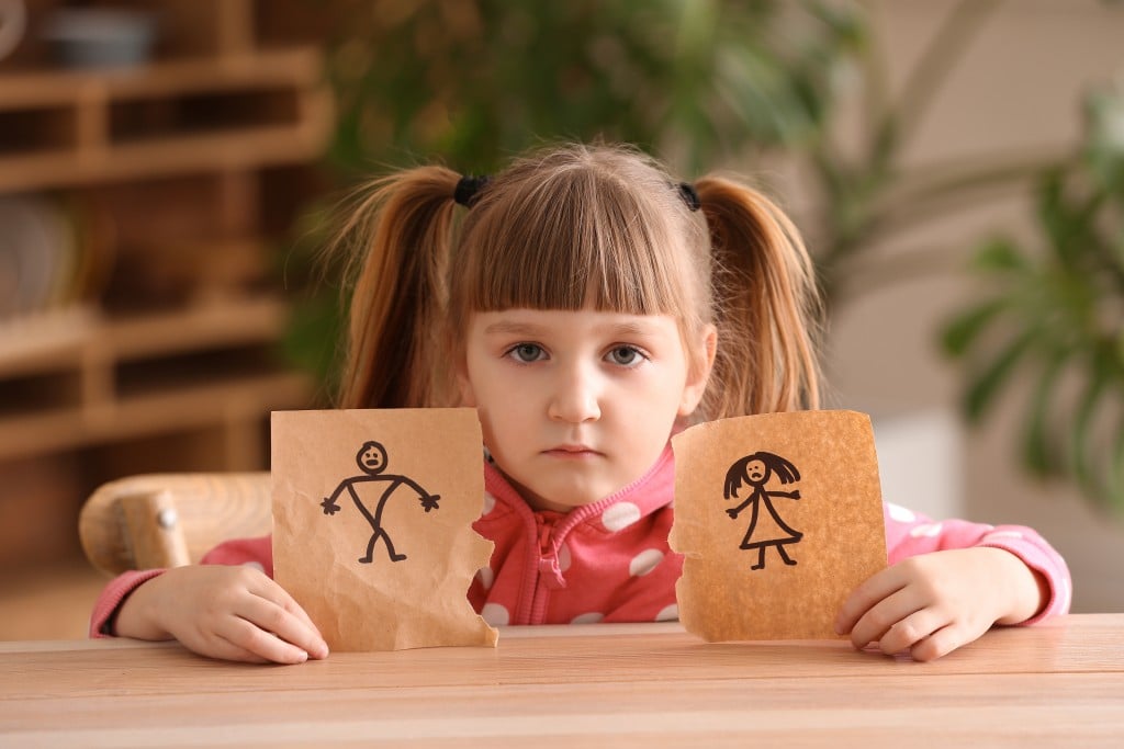 Sad Little Girl With Torn Drawing Of Family At Table. Concept Of