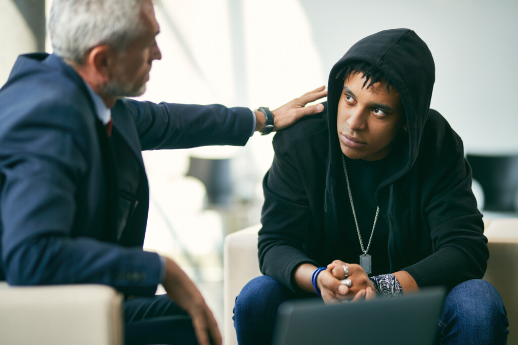 African American Teenage Boy On Individual Therapy Session With Mental Health Professional.