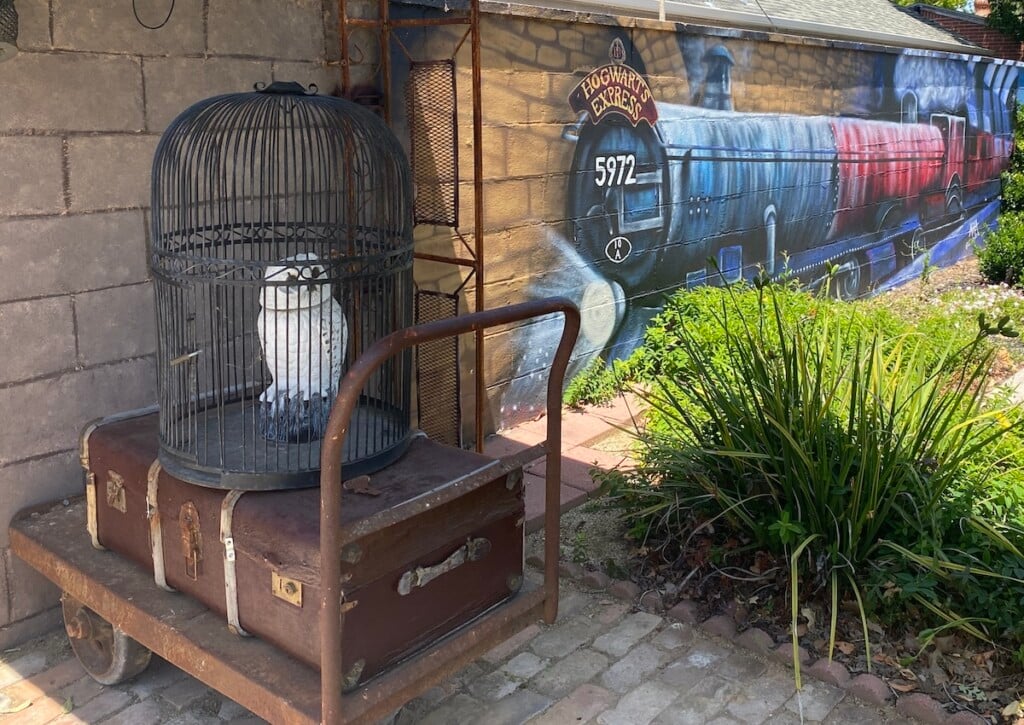 A white owl, luggage cart and train mural in Sacramento's Diagon Alley