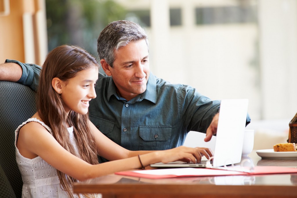 Father And Teenage Daughter Looking At Laptop Together Monitor