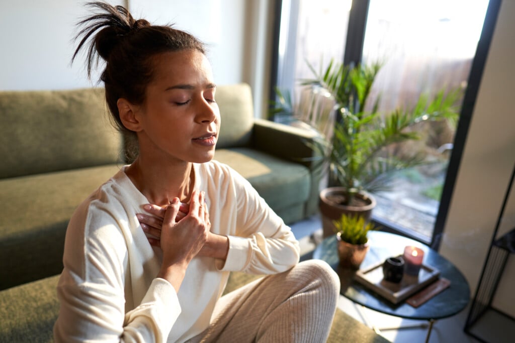 Mixed Race Woman Meditating At Home With Eyes Closed