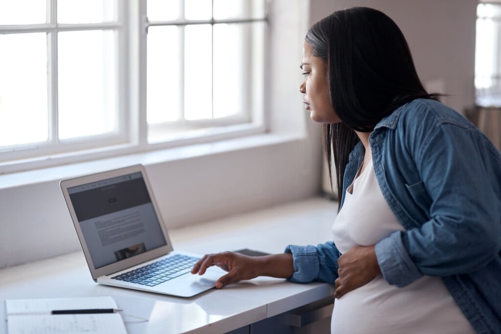 The Doctor Said To Take It Easy, Not Do Nothing. A Pregnant Woman Using Her Laptop While Sitting At Home.