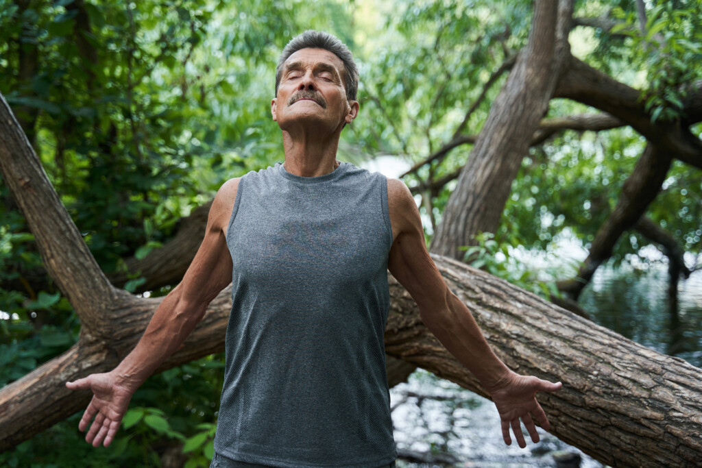 Senior Man With Closed Eyes Spread His Hands And Breathing Summer Freshness