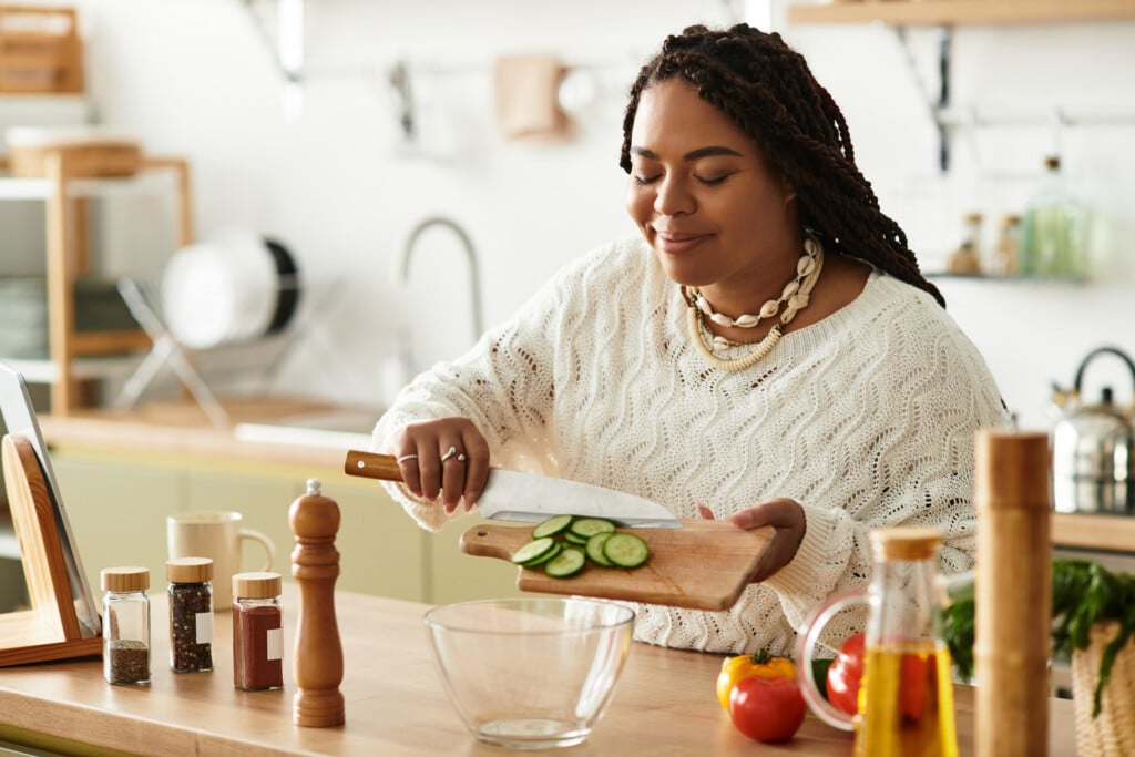 A Young African American Woman Skillfully Chops Fresh Vegetables For A Nutritious Salad At Home.