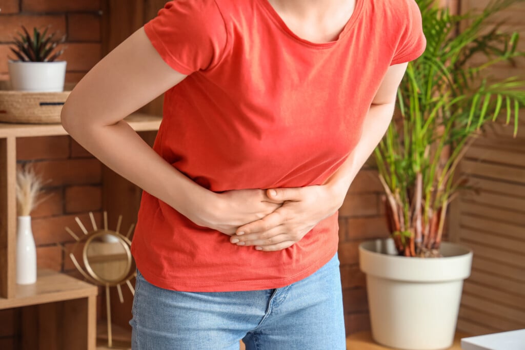 Young Woman Suffering From Stomach Ache At Home, Closeup