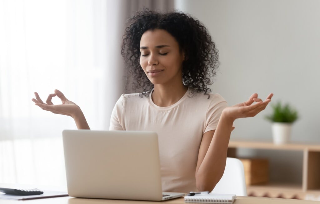 Calm African American Woman Meditating At Desk With Laptop