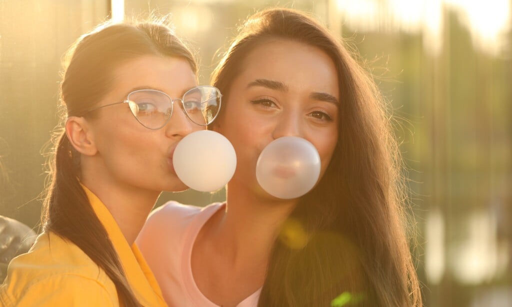 Beautiful Young Women Blowing Bubble Gums Outdoors On Sunny Day