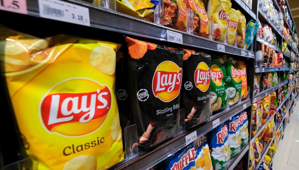 Various Brands Of Local And Imported Potato Chips And Snacks On The Shelf In A Grocery Store