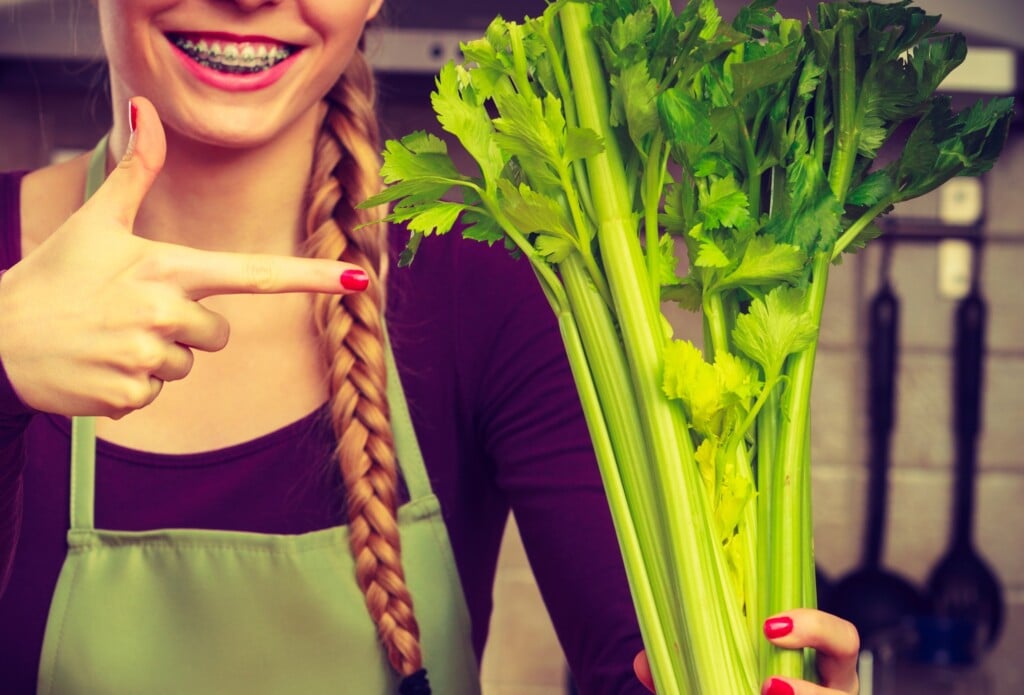 Woman In Kitchen Holds Green Celery