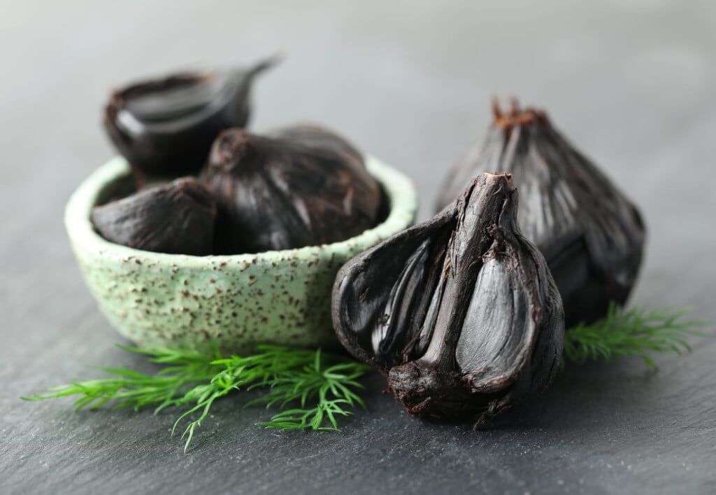 Bowl With Black Garlic (allium Sativum) On Table