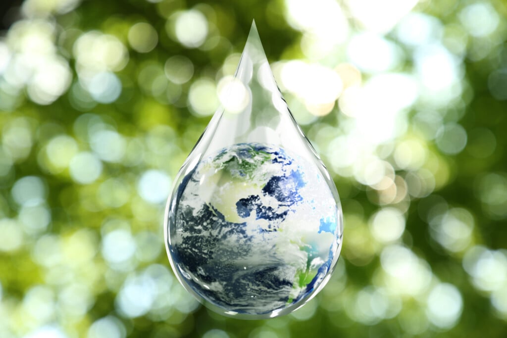 Save Water Concept. Earth Inside Drop Against Blurred Green Background
