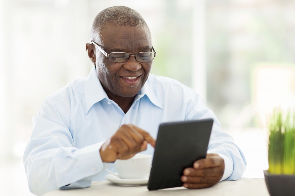 Senior African American Man Using Tablet Computer At Home