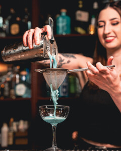 A smiling bartender pours a cocktail