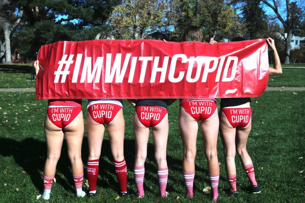 Runners wear Cupid's Undie Run underwear and stand with a banner reading #IMWITHCUPID