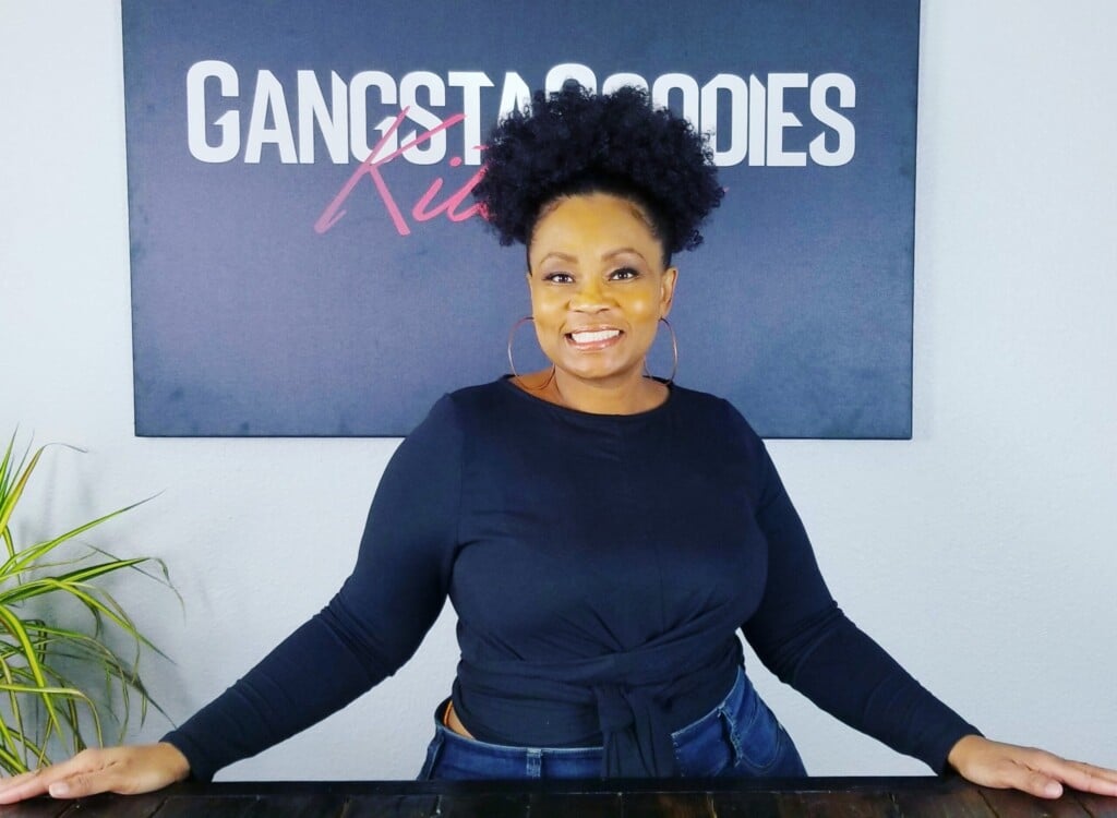 Shelia Johnson standing in front of a Gangsta Goodies Kitchen sign.