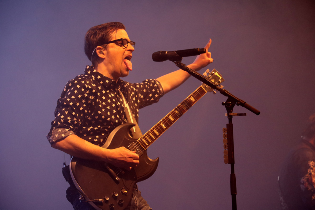 Weezer frontman Rivers Cuomo plays guitar onstage