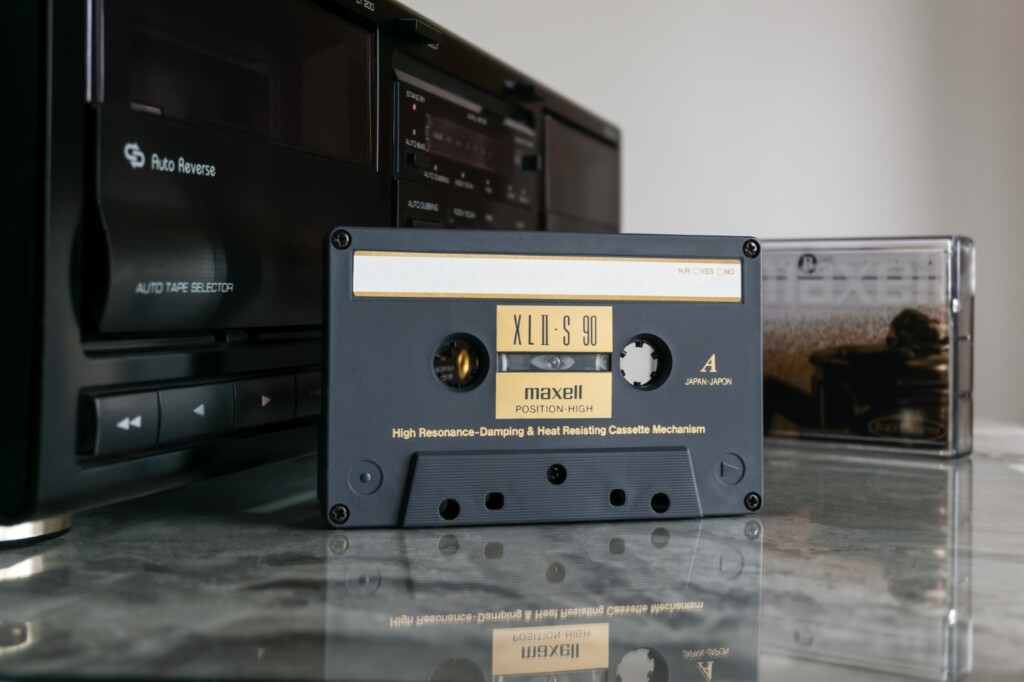 Maxell Xl Ii S 90 Audio Cassette In Front Of Cassette Deck On Polished Marble Tabletop With Reflection