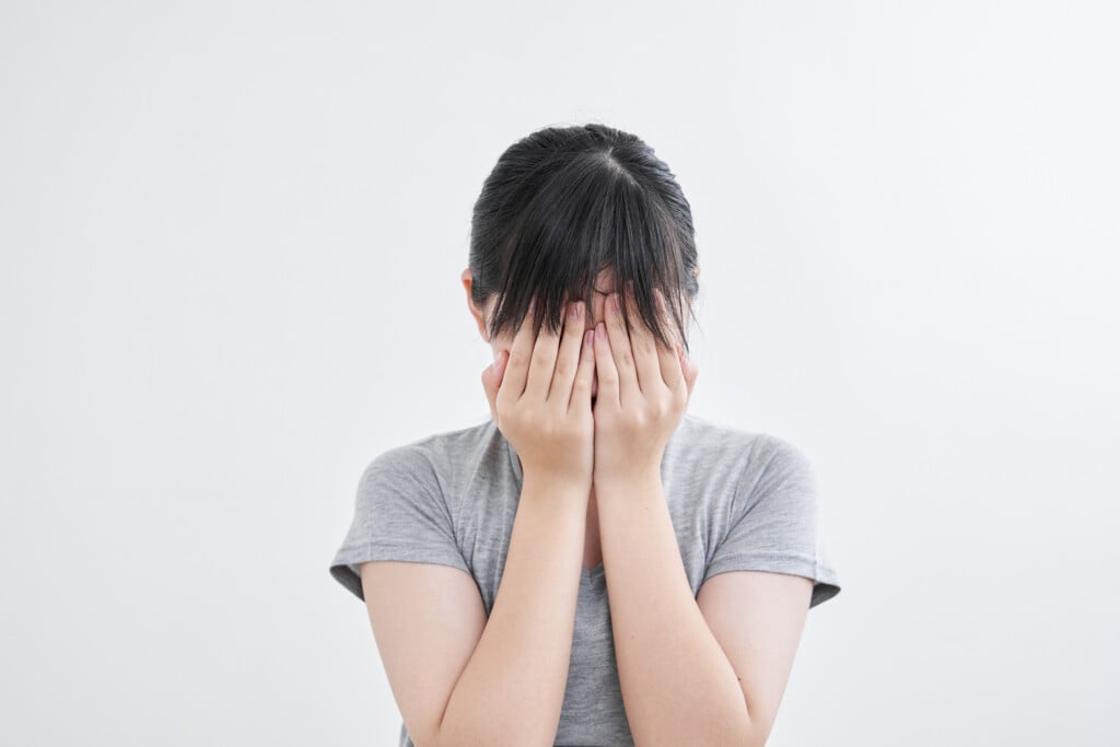 teen girl hiding her face, for article on making friends freshman year of high school