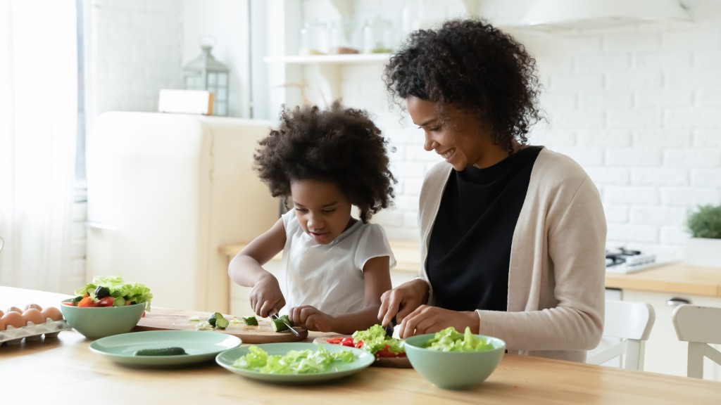 A young girl and her mom make salads together