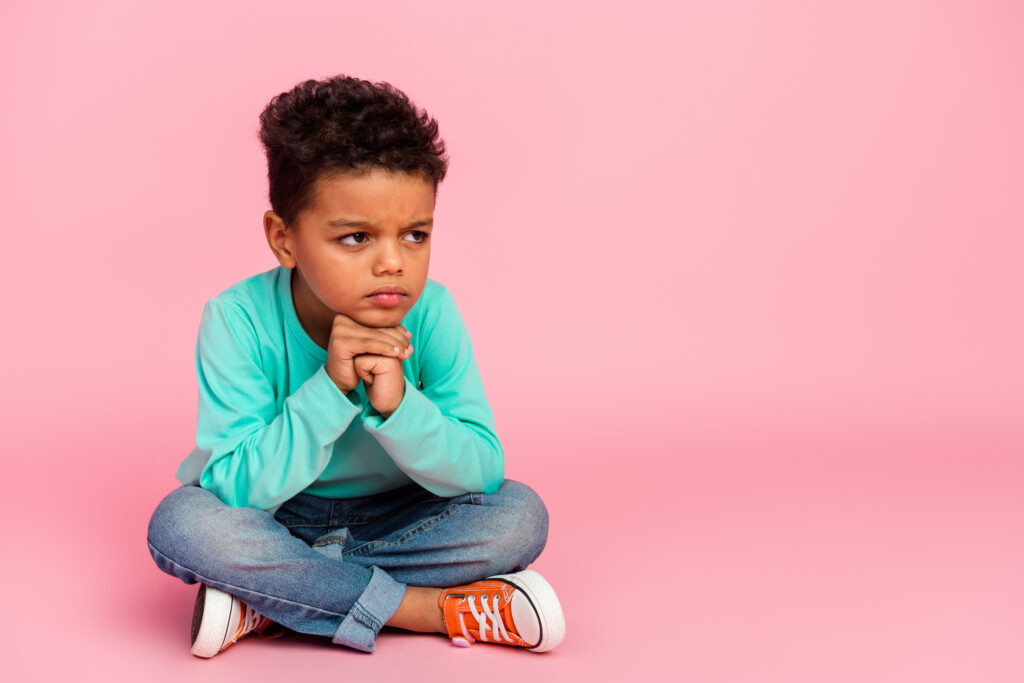 a thoughtful young boy on pink background