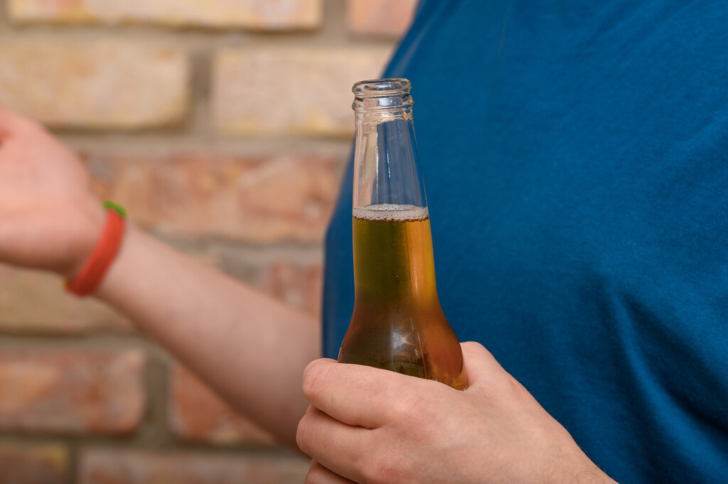 a person holding a bottle of beer, close up