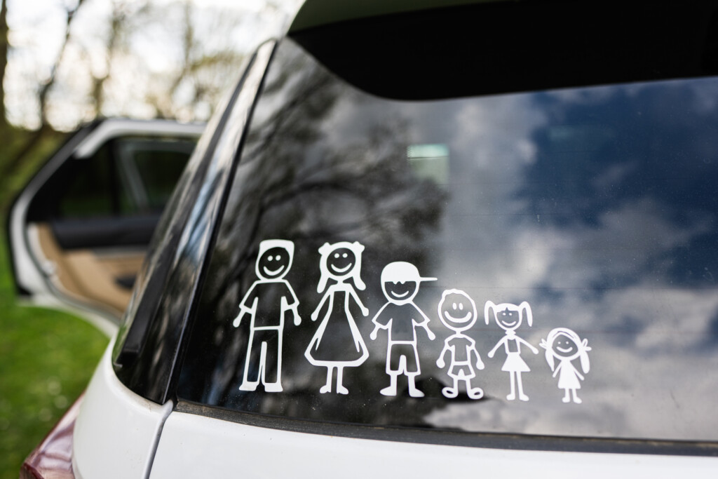 stick figure family on back of car, two parents and four kids
