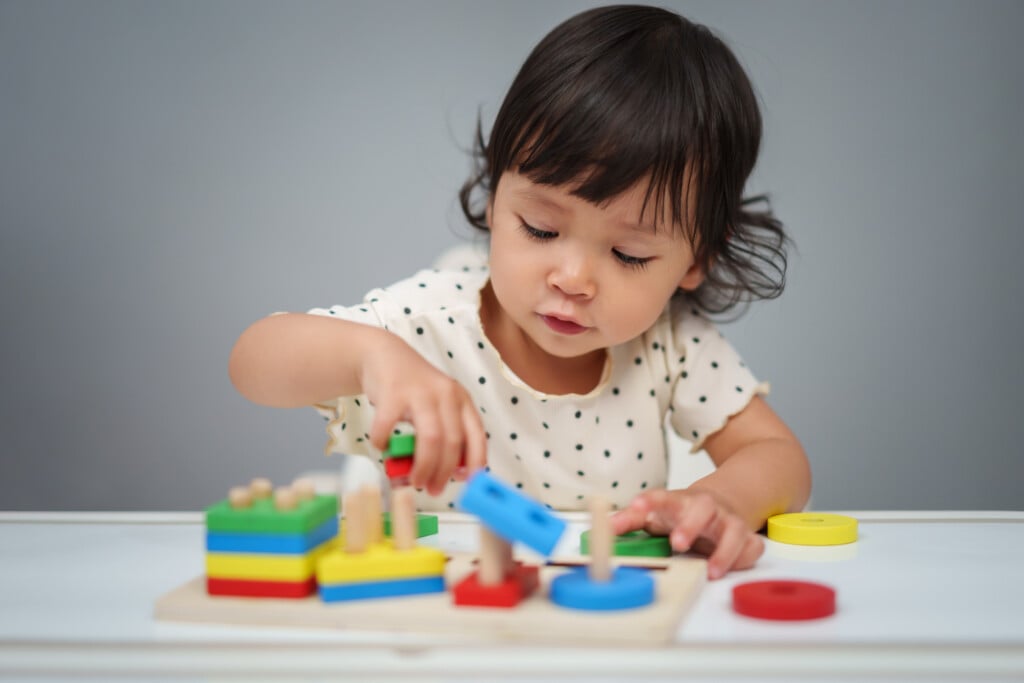 toddler playing with colorful block type toy