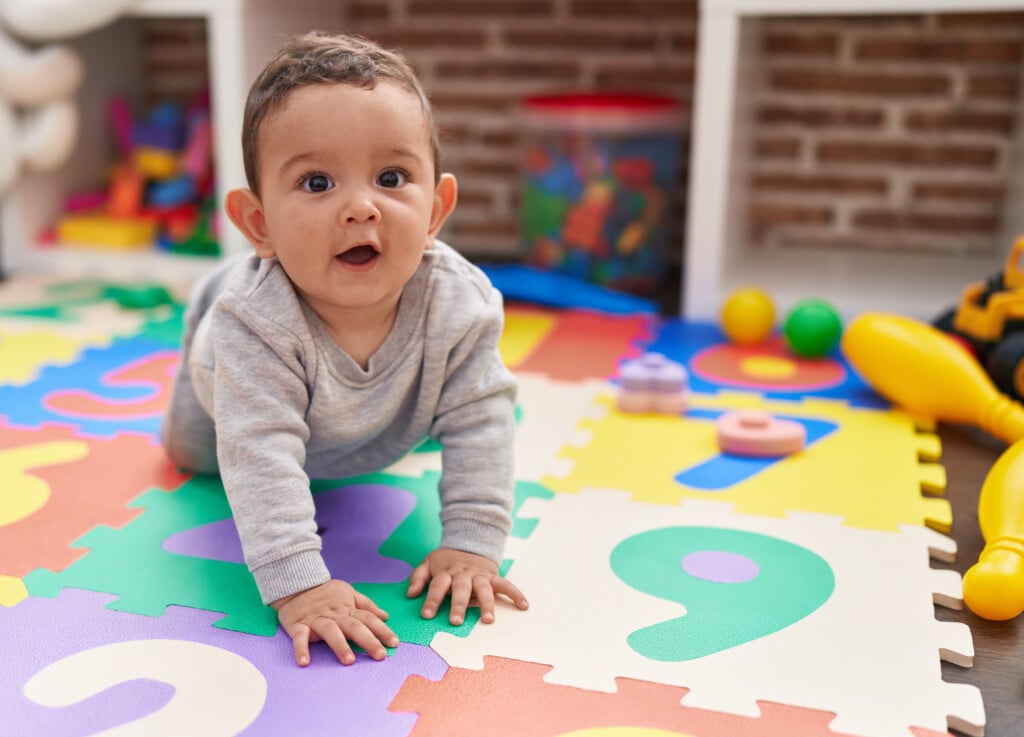 baby crawling on playmat in classroom
