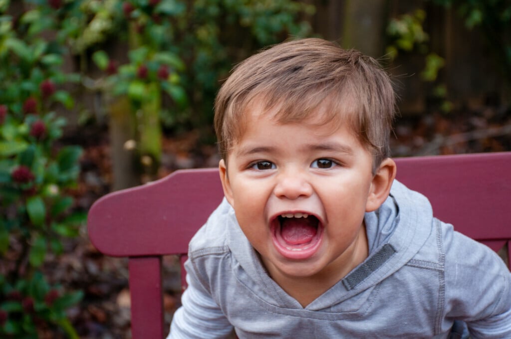 toddler sitting in chair, with open mouth like he might bite something