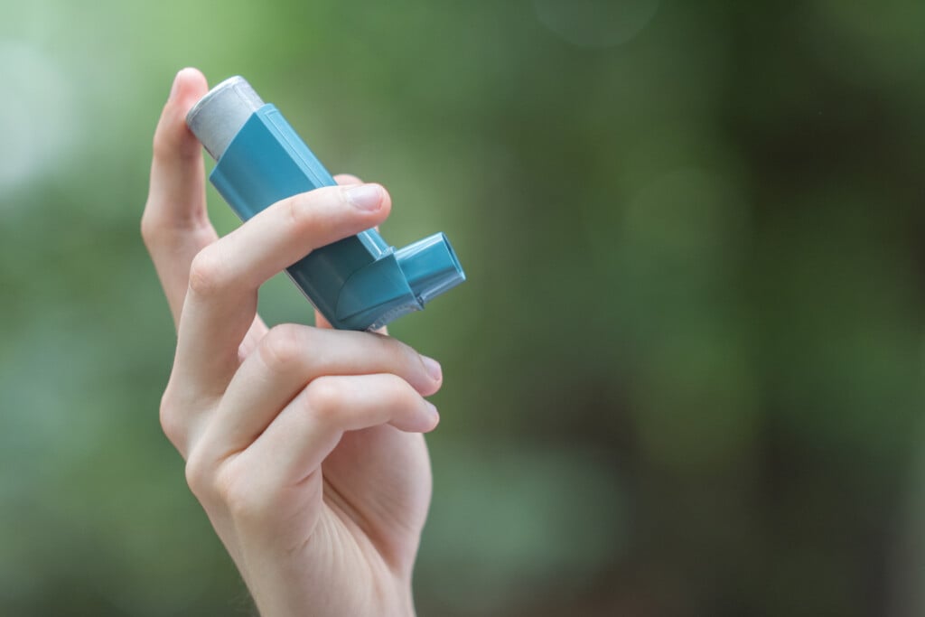 a hand holding an asthma inhaler