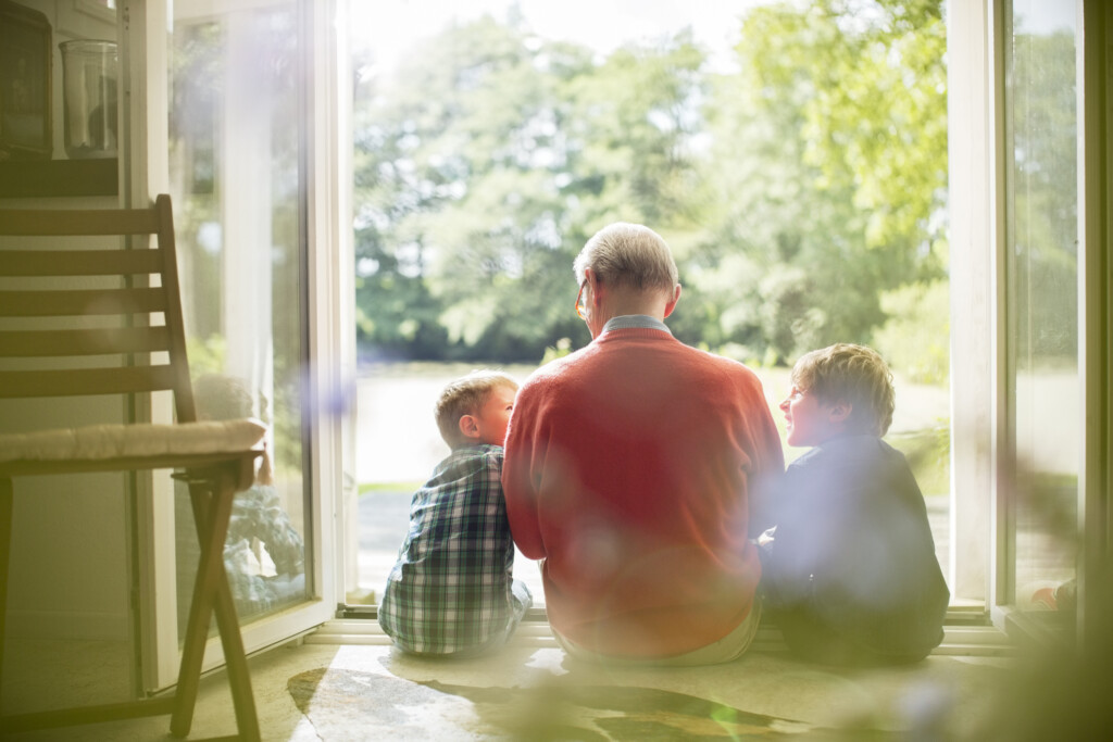 Grandfather And Grandsons Sitting In Doorway