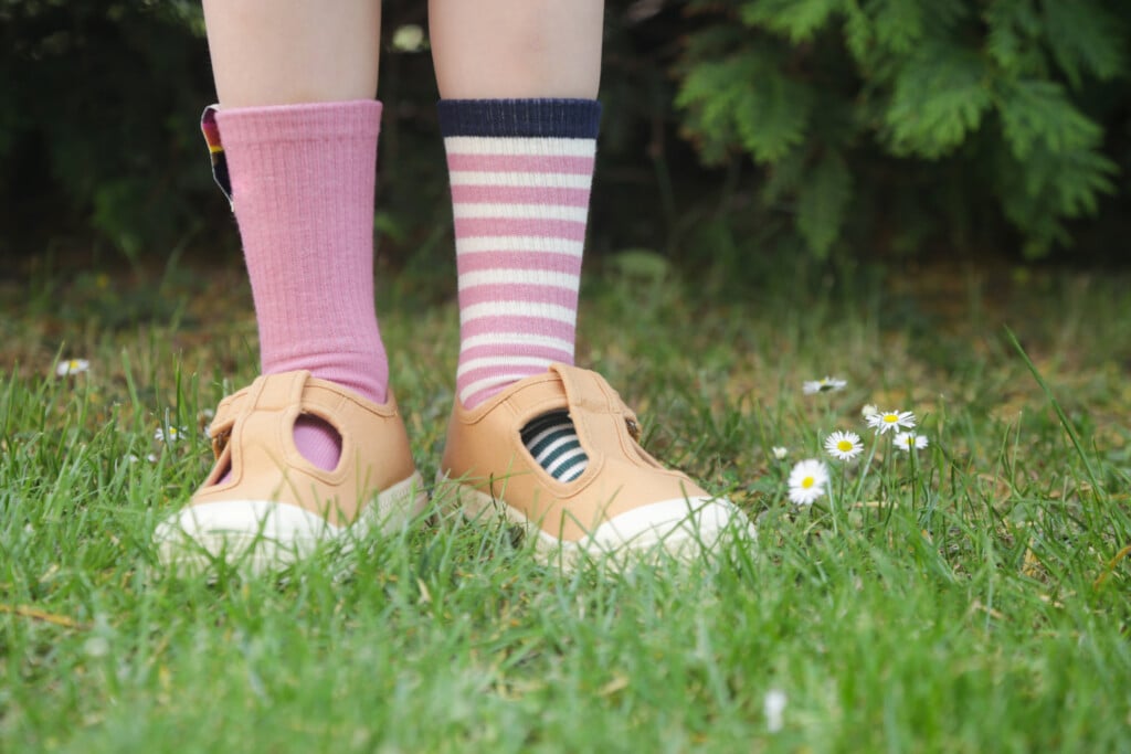 close up of child's feet wearing pink shoes and unmatched socks