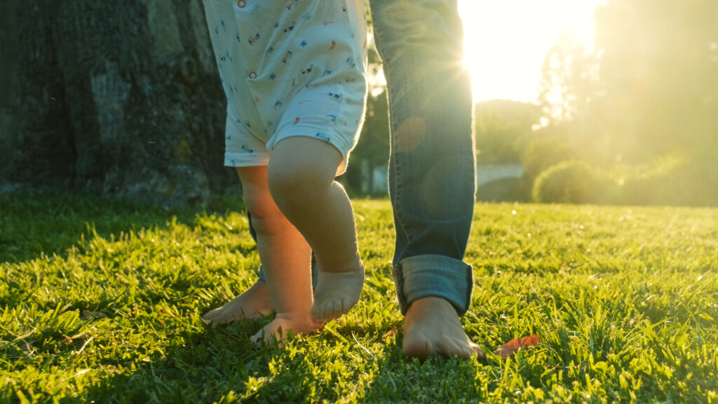 Walking Children's Bare Feet On A Green Lawn Close Up.